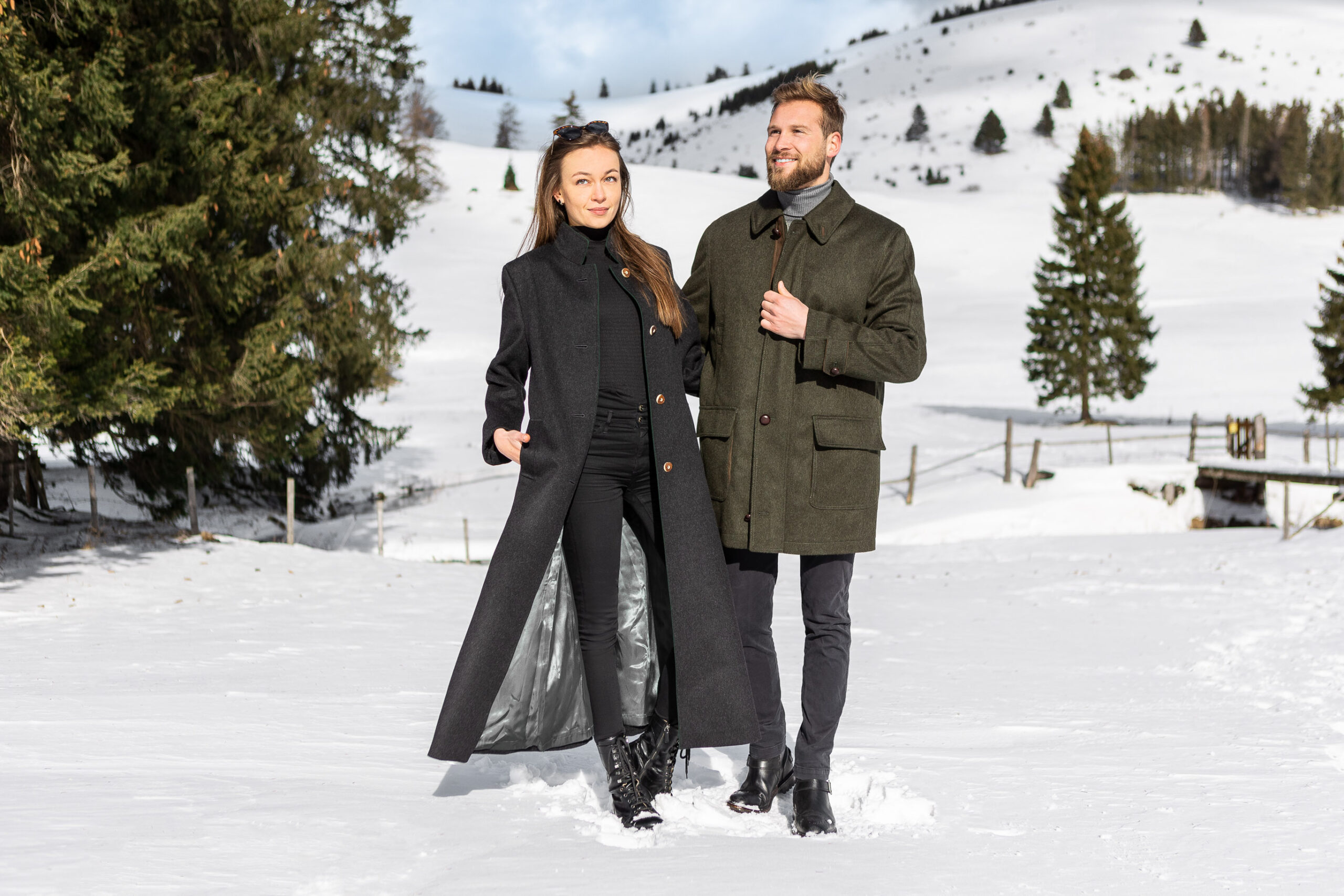 young couple wearing loden coats in austrian alps in the snow